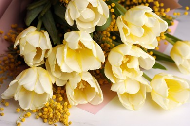 Photo of Bouquet with beautiful tulips and mimosa flowers on white marble table