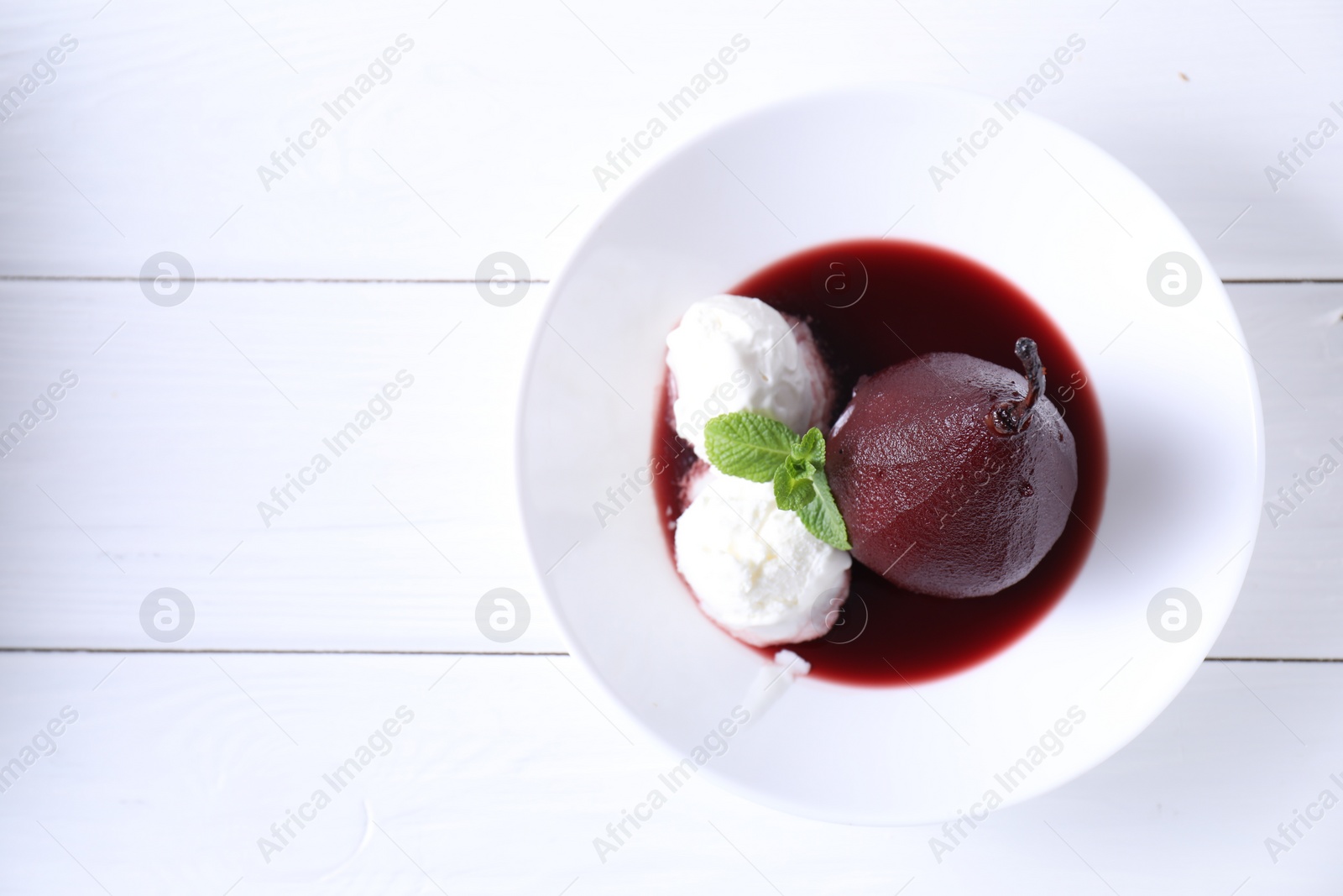 Photo of Tasty red wine poached pear with mint and Ice cream on white wooden table, top view. Space for text