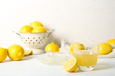 Photo of Glass of lemon juice and fresh fruit on light table
