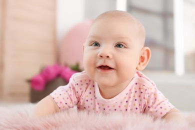 Adorable baby girl lying on fluffy rug