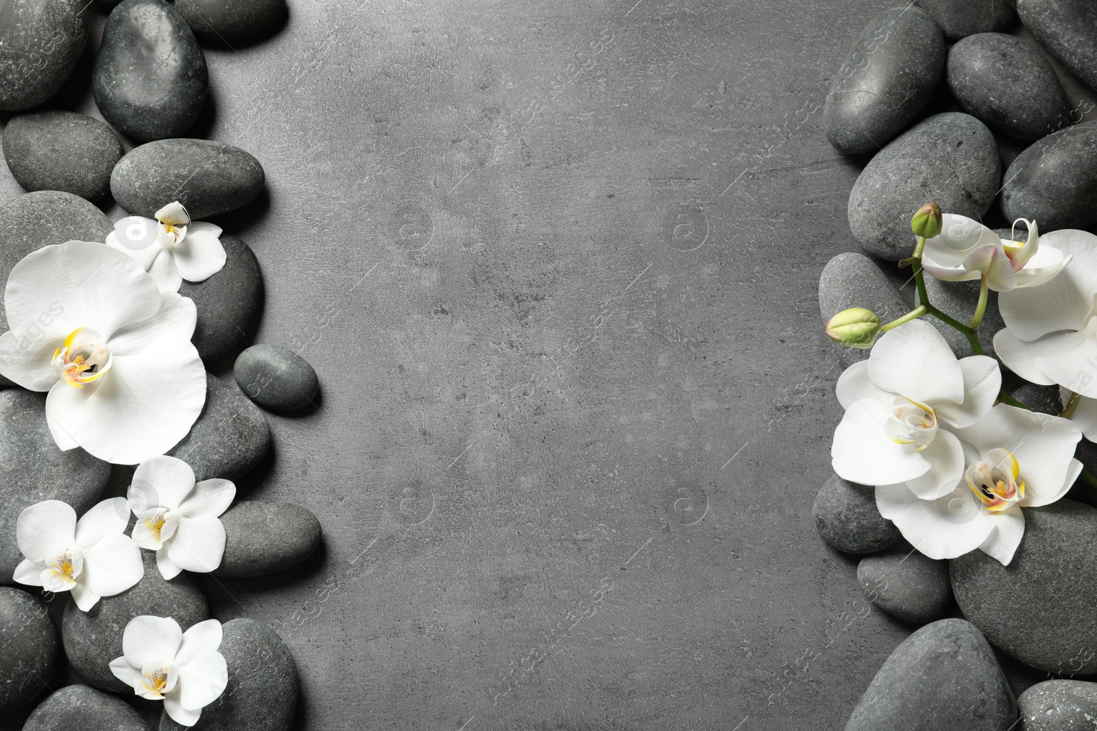 Photo of Flat lay composition with spa stones and orchid flowers on grey background. Space for text