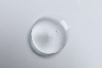 Photo of Drop of cosmetic oil on white background, top view