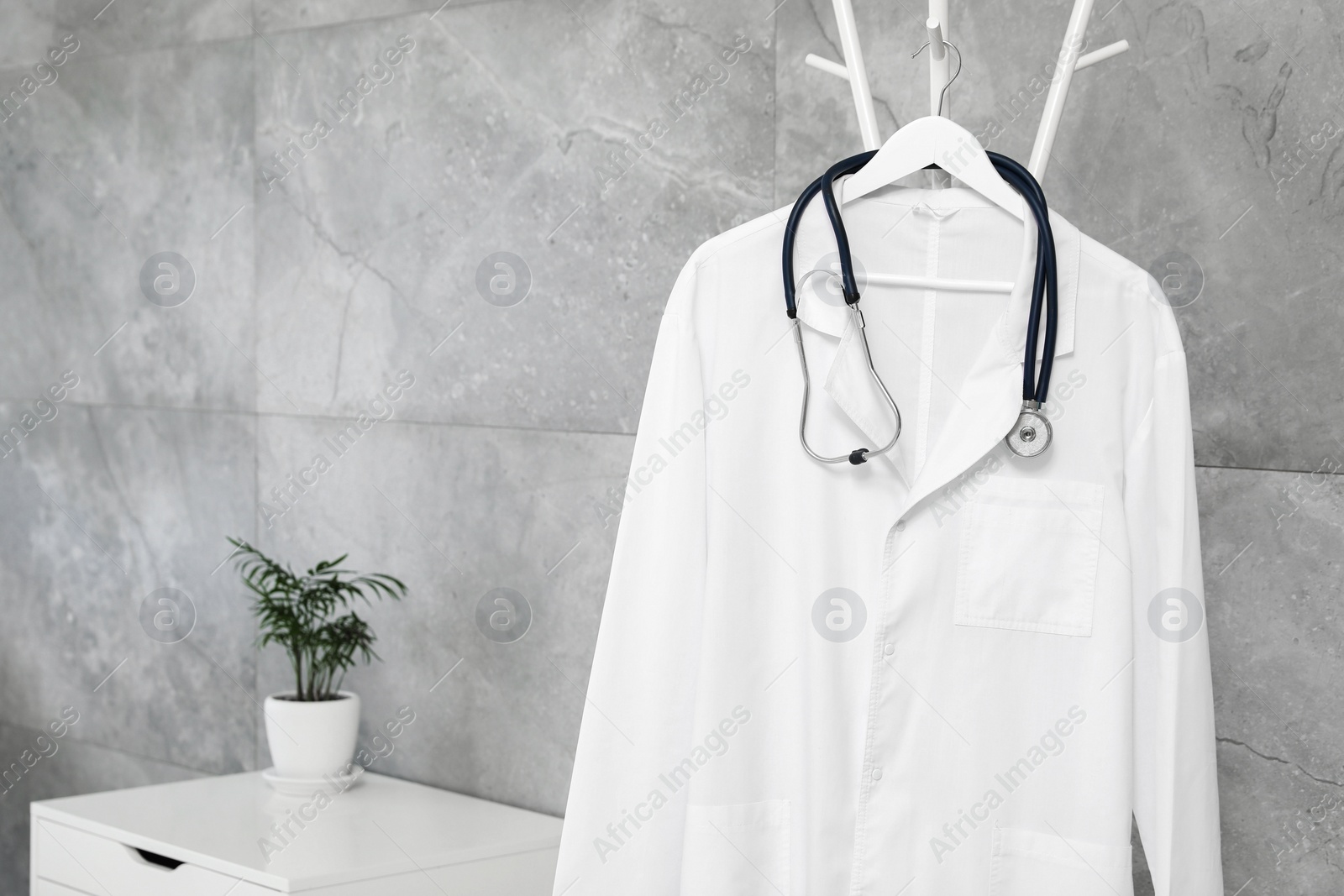 Photo of White doctor's gown and stethoscope on rack in clinic