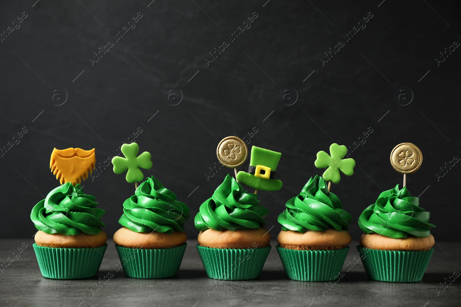 Photo of Delicious decorated cupcakes on grey table. St. Patrick's Day celebration