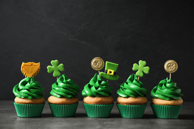 Photo of Delicious decorated cupcakes on grey table. St. Patrick's Day celebration