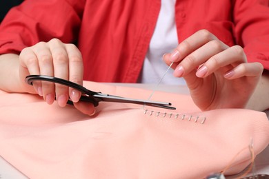 Woman cutting sewing thread over cloth, closeup