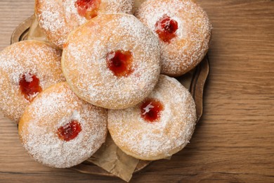 Photo of Delicious donuts with jelly and powdered sugar on wooden table, top view