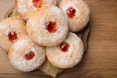 Delicious donuts with jelly and powdered sugar on wooden table, top view