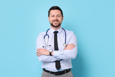 Photo of Smiling doctor with stethoscope on light blue background