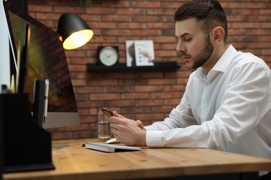 Photo of Forex trader working with smartphone and computer in office