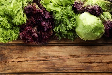 Different sorts of lettuce on wooden table, flat lay. Space for text