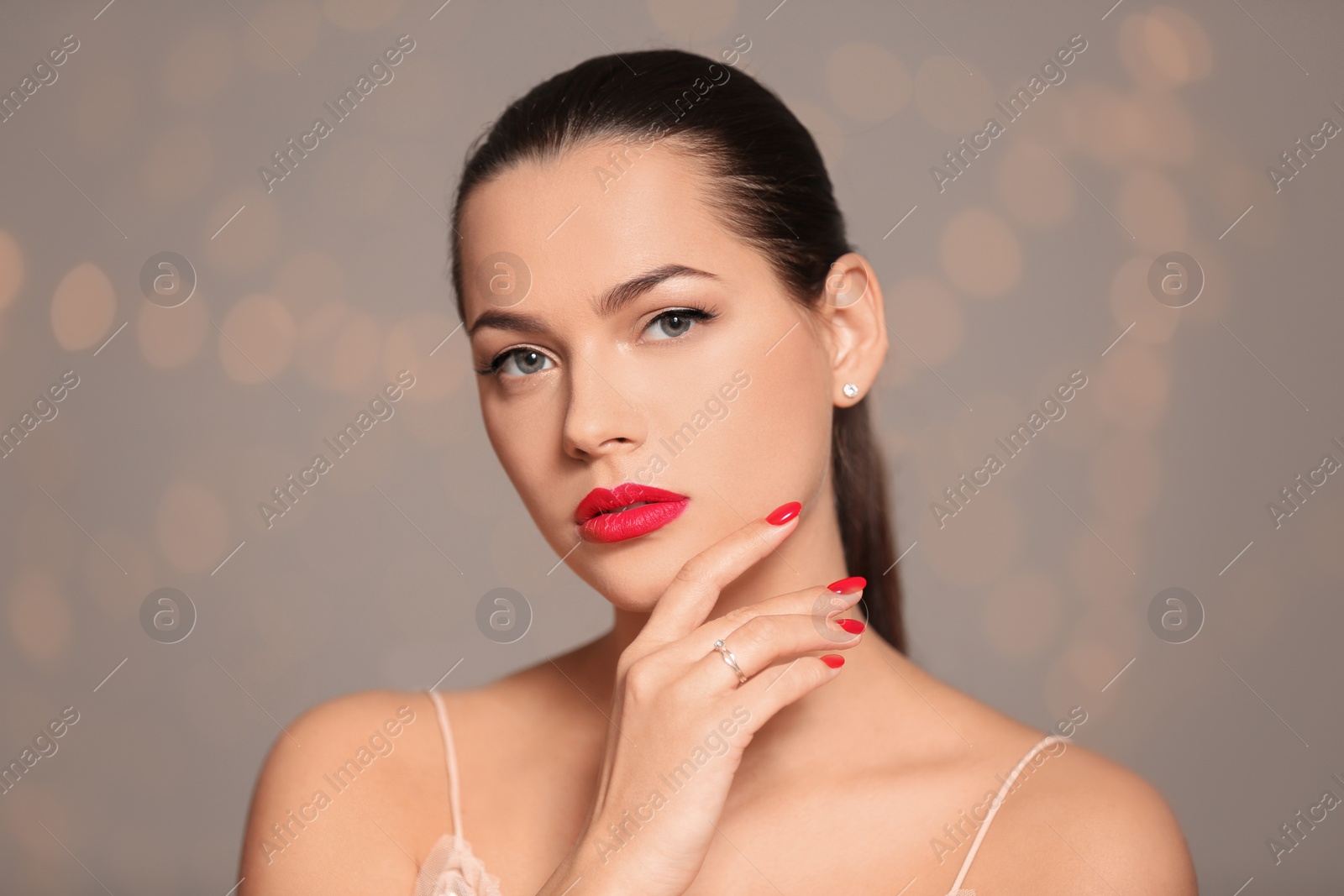 Photo of Portrait of beautiful young woman with bright manicure on blurred background. Nail polish trends