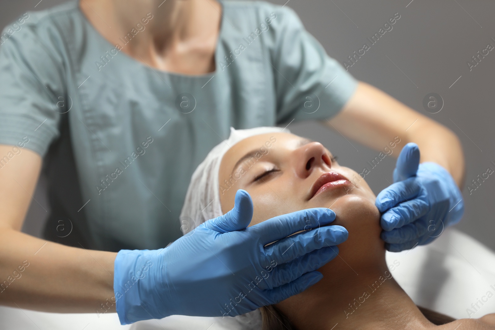 Photo of Young woman receiving facial massage in salon