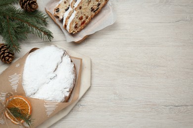 Photo of Wrapped Christmas Stollen with decoration on wooden table, flat lay. Space for text