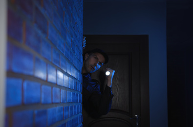 Male security guard with flashlight in dark corridor