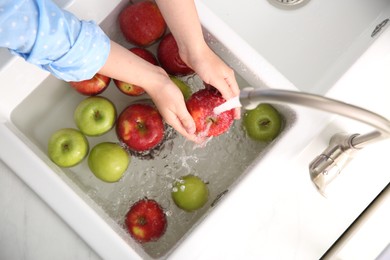 Woman washing fresh apples in kitchen sink, top view