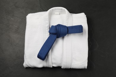 Photo of Blue karate belt and white kimono on gray background, top view