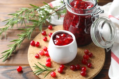 Photo of Cranberry sauce, fresh berries and rosemary on wooden table