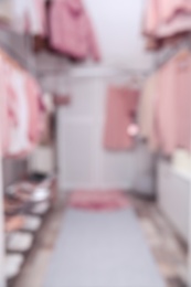 Blurred view of modern dressing room with different stylish clothes and accessories