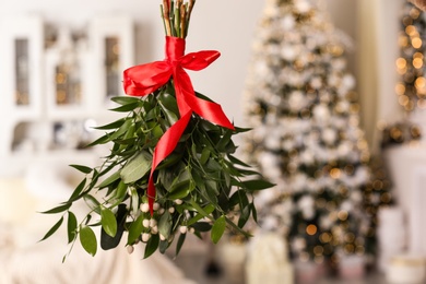 Photo of Mistletoe bunch with red bow hanging in room decorated for Christmas