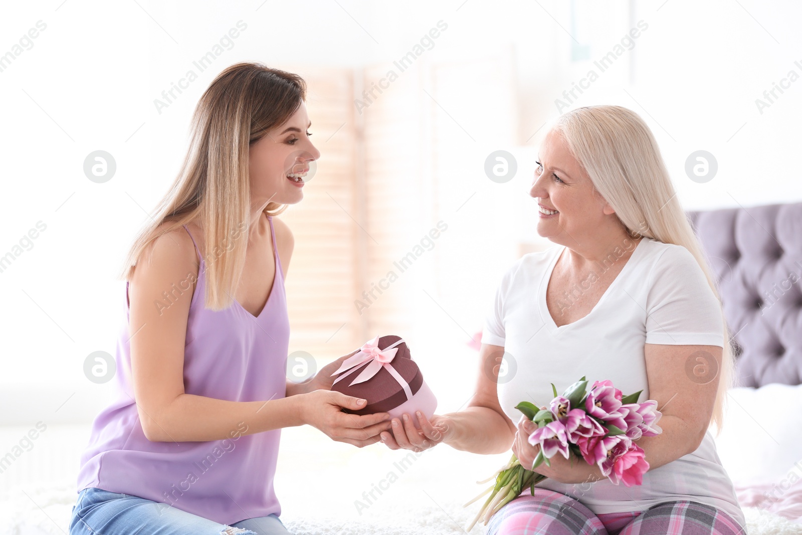 Photo of Daughter congratulating happy mature woman on Mother's Day at home