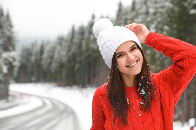 Photo of Young woman in warm sweater outdoors on snowy day, space for text. Winter vacation