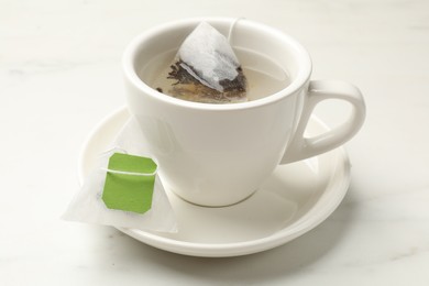 Photo of Tea bag in cup on white table, closeup