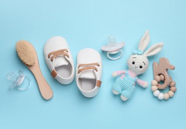 Photo of Flat lay composition with pacifiers and other baby stuff on light blue background