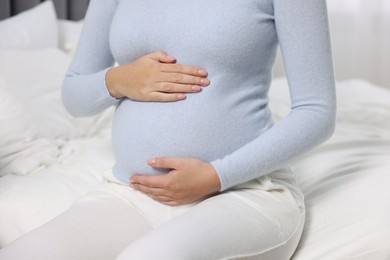 Photo of Pregnant woman on white bed, closeup view