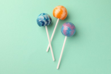 Tasty lollipops on turquoise background, flat lay