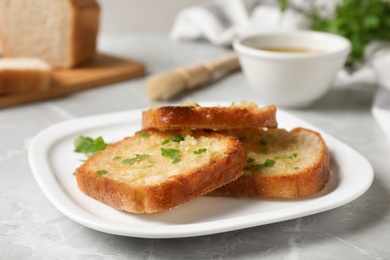 Photo of Slices of toasted bread with garlic and herb on light grey marble table, closeup