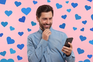 Long distance love. Man chatting with sweetheart via smartphone on pink background. Hearts around him