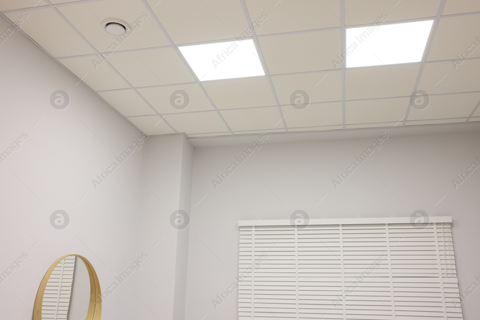 Photo of White ceiling with PVC tiles and lighting indoors, low angle view