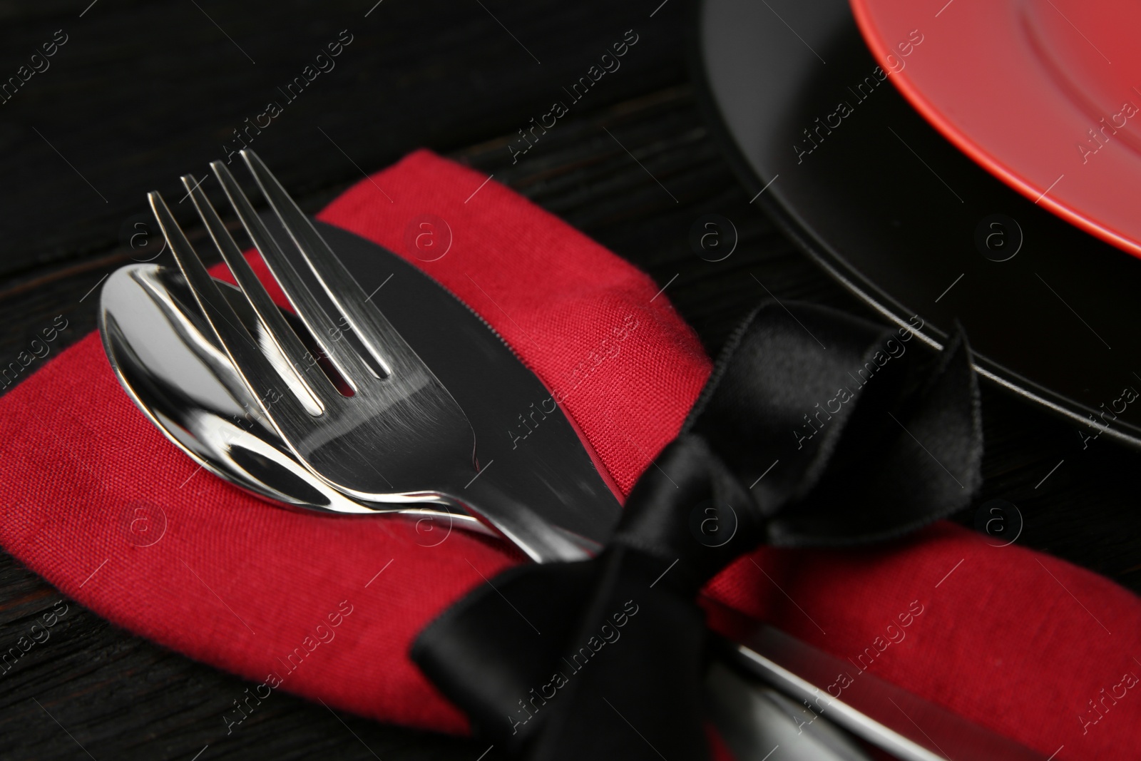 Photo of Cutlery set and dishware on black wooden table, closeup