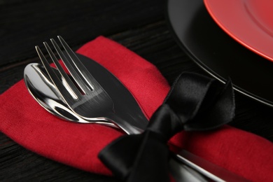 Photo of Cutlery set and dishware on black wooden table, closeup