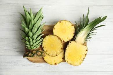 Photo of Slices of fresh pineapple on white wooden table, flat lay