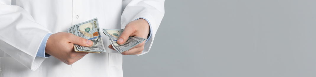 Doctor with bribe on grey background, closeup. Banner design