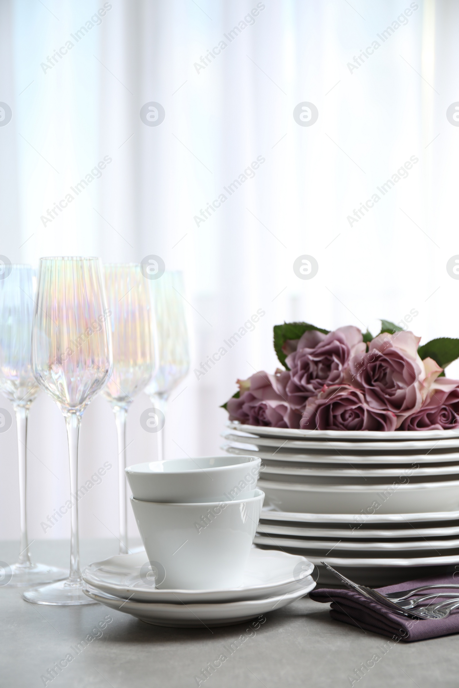 Photo of Set of glasses and dishes with flowers on light grey table