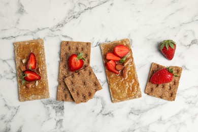 Photo of Fresh rye crispbreads with jam, strawberries and almonds on white marble table, flat lay