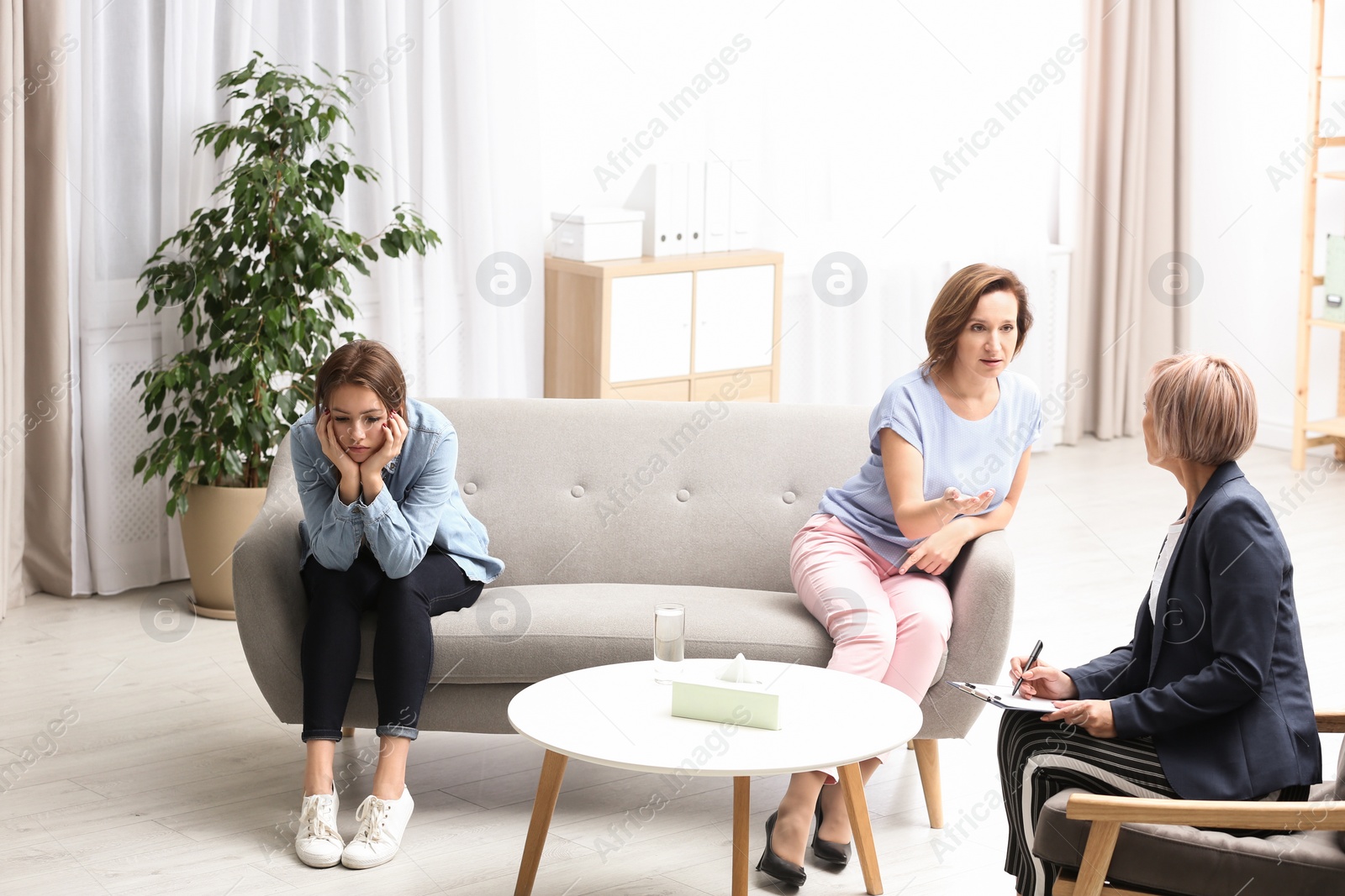 Photo of Psychotherapist working with teenage girl and her mother in office