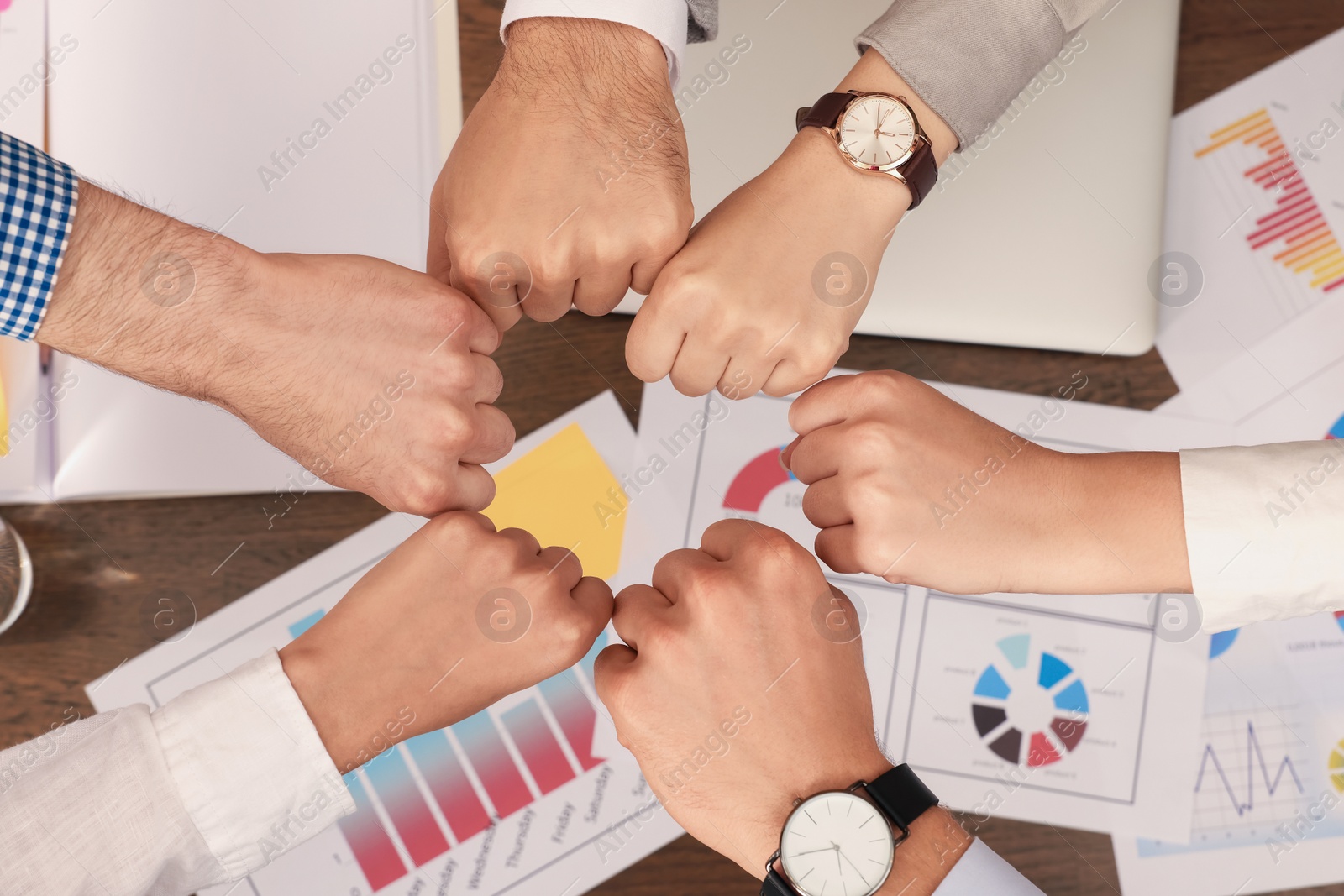 Photo of Office employees joining hands at work, top view