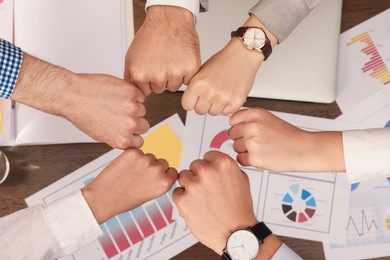 Photo of Office employees joining hands at work, top view