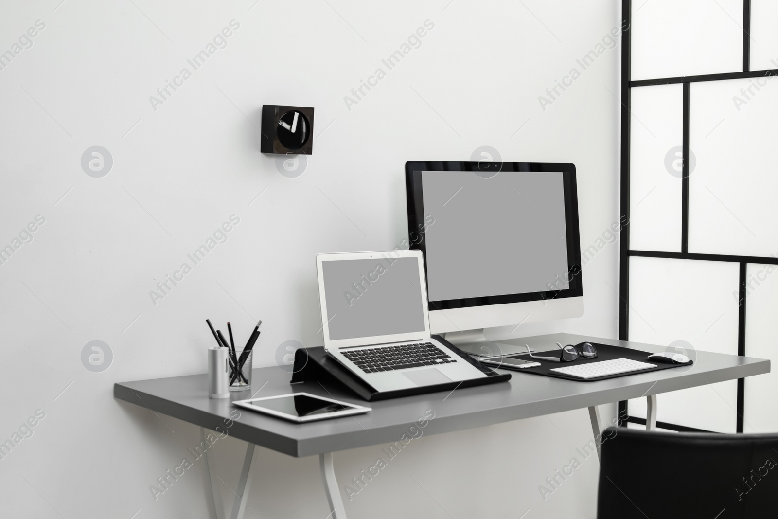 Photo of Modern workplace interior with computers on table. Space for text