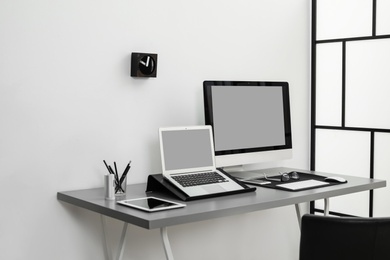 Photo of Modern workplace interior with computers on table. Space for text