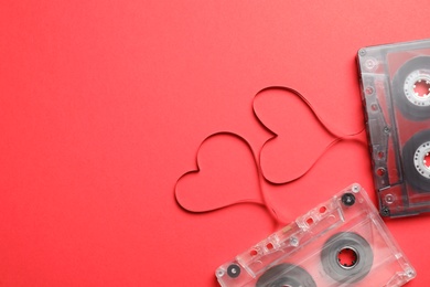 Photo of Music cassettes and hearts made of tape on red background, flat lay with space for text. Listening love songs