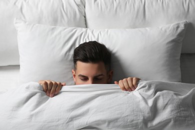 Photo of Handsome man sleeping under soft blanket in bed at home