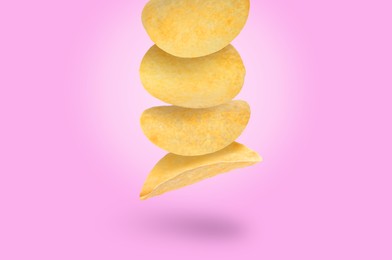 Stack of tasty potato chips falling on light violet background