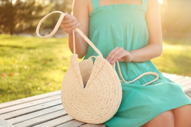 Photo of Young woman with stylish straw bag in park, closeup