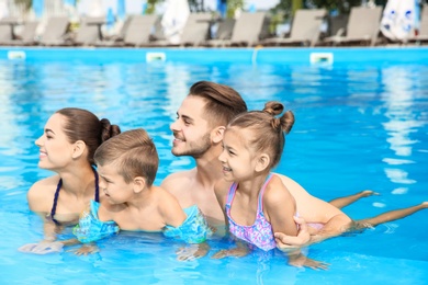 Young family with little children in swimming pool on sunny day