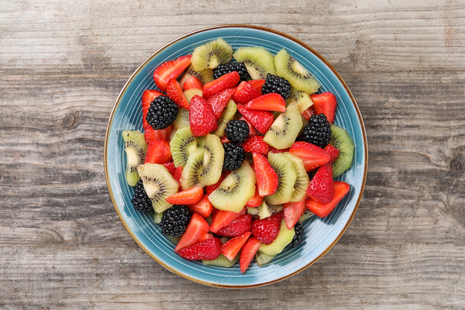 Plate of delicious fresh fruit salad on wooden table, top view Photo of Plate of delicious fresh fruit salad on wooden table, top view